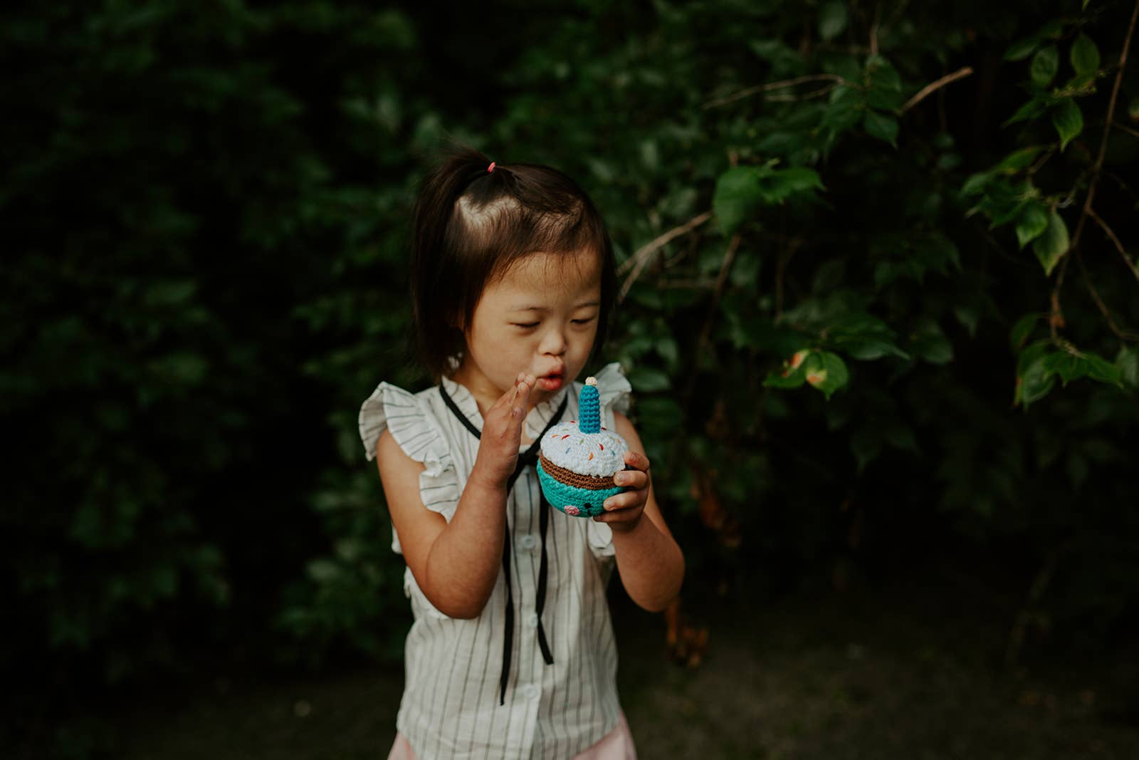 Little girl pretending to blow the cupcake rattle candle